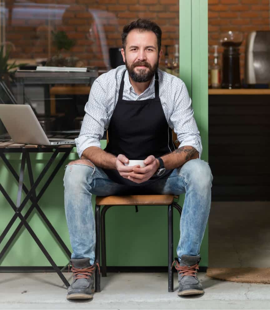 Small business owner sitting at front of his store
